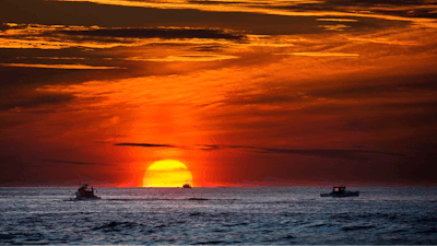 The sun rises over fishing boats in the Atlantic Ocean, Sept. 8, 2022, off of Kennebunkport, Maine.