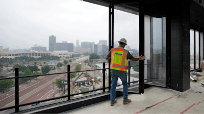 A worker opens the windows on the top floor of the new Godfrey Hotel, June 27, 2023, in Detroit.
