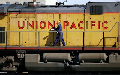 A maintenance worker walks on the side of a locomotive in the Union Pacific Railroad fueling yard in north Denver, Oct. 18, 2006.