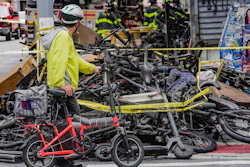 A biker stops to look at a pile of e-bikes in the aftermath of a fire in Chinatown, which authorities say started at an e-bike shop and spread to upper-floor apartments, Tuesday June 20, 2023, in New York.