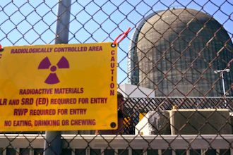 A sign warning of radioactive materials is seen on a fence around a nuclear reactor containment building, April 26, 2021, a few days before it stopped generating electricity at Indian Point Energy Center, in Buchanan, N.Y.