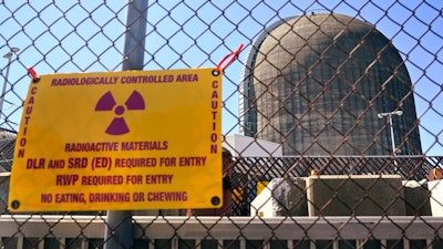A sign warning of radioactive materials is seen on a fence around a nuclear reactor containment building, April 26, 2021, a few days before it stopped generating electricity at Indian Point Energy Center, in Buchanan, N.Y.