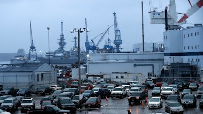 A shipyard worker, below center, walks to his car at the end of a workday at Bath Iron Works in Bath, Maine, Tuesday, Jan. 3, 2017.