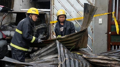 Firemen arrange steel sheets from a factory that caught fire in Quezon city, Philippines on Thursday, Aug. 31, 2023.