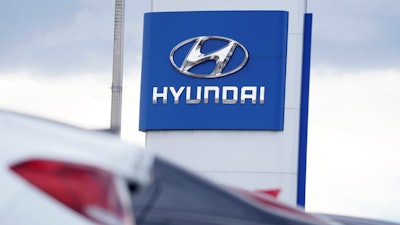 The Hyundai company logo hangs over a long row of cars at a car dealership in Centennial, Colo., Sunday, Dec. 20, 2020.