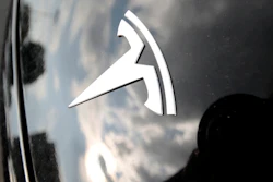 Clouds are reflected above the company logo on the hood of a Tesla vehicle outside a showroom in Littleton, Colo.