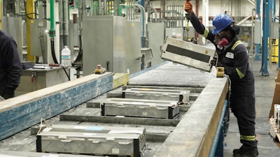 This undated photo provided by Ascend Elements shows a team member loading used electric vehicle battery modules onto a massive shredder at the Ascend Elements battery recycling facility in Covington, Ga.