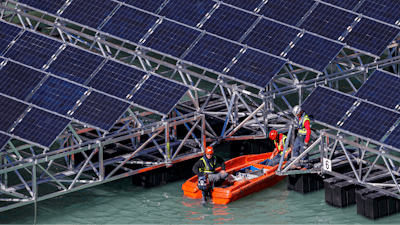 Workers assemble floating barges with solar panels on the 'Lac des Toules', an alpine reservoir lake, in Bourg-Saint-Pierre, Switzerland, Tuesday, Oct. 8, 2019.