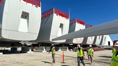 Workers walk by components of wind turbines being assembled at the State Pier in New London, Conn., on Wednesday, Oct. 4, 2023. The turbines will make up South Fork Wind Farm and eventually provide energy to New York.