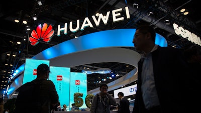 Attendees walk past a display for 5G services from Chinese technology firm Huawei at the PT Expo in Beijing, on Oct. 31, 2019.