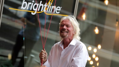 Richard Branson, of Virgin Group, prepares to unfurl a banner during a naming ceremony for the Brightline train station, to be renamed as Virgin MiamiCentral in Miami on April 4, 2019.