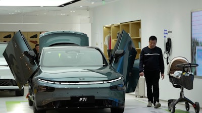 A visitor walks near the P7i electric sedan from Chinese automaker Xpeng at a show room in Beijing, Thursday, April 13, 2023.