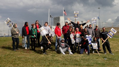 With arms outstretched, U.S. Sen. John Fetterman, D-Pa., poses for a photo with striking workers as he visits the United Auto Workers picket line at the Stellantis Toledo Assembly Complex on Friday, Oct. 20, 2023, in Toledo, Ohio.