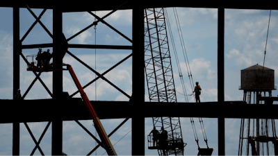 Iron workers construct the framework of a $4 billion Panasonic EV battery plant, May 18, 2023, near DeSoto, Kan.