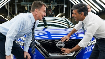 Britain's Prime Minister Rishi Sunak, right and Chancellor of the Exchequer Jeremy Hunt attach a Nissan badge to a car as they visit the car manufacturer Nissan, in Sunderland, England, Friday, Nov. 24, 2023.