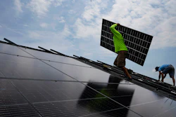 Nicholas Hartnett, owner of Pure Power Solar, carries a panel as he and Brian Hoeppner, right, install a solar array on the roof of a home in Frankfort, Ky., July 17, 2023.