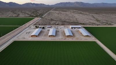Bales of hay are stored under shelters at Al Dahra Farms, Tuesday, Oct. 17, 2023, in the McMullen Valley in Wenden, Ariz.