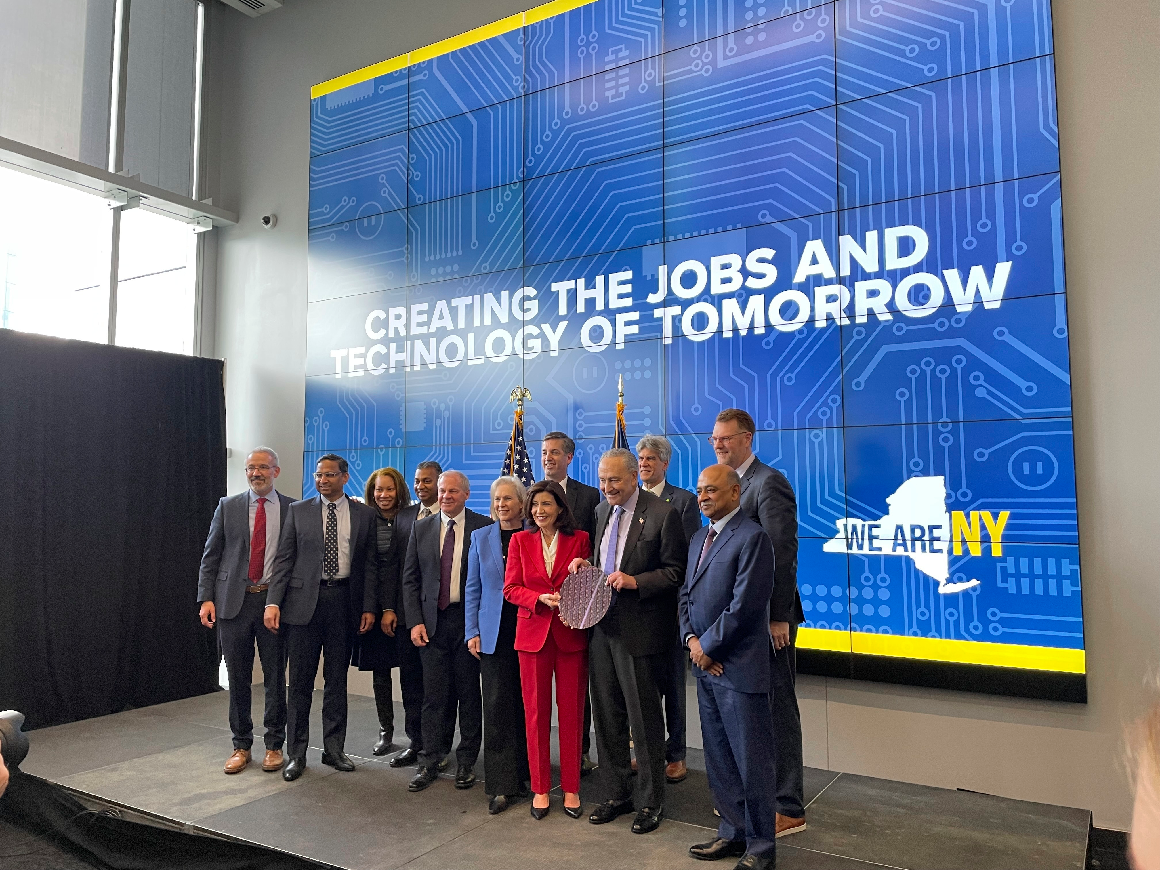 New York Gov. Kathy Hochul and Sen. Chuck Schumer hold a silicon wafer and pose for a photo with lawmakers and leaders from the semiconductor industry during an event at NY CREATES&rsquo; Albany NanoTech Complex.