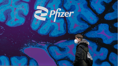 A man walks by Pfizer headquarters, Friday, Feb. 5, 2021 in New York.