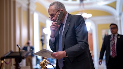 Senate Majority Leader Chuck Schumer, D-N.Y., talks on his phone on the way to a closed-door Democratic strategy session, at the Capitol in Washington, Wednesday, March 20, 2024.