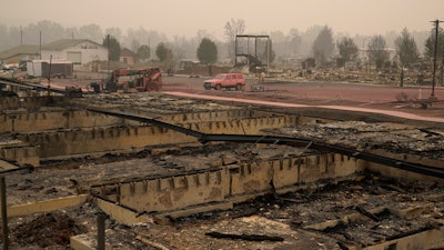 Pink fire retardant covers a car at an area destroyed by the Almeda Fire, Friday, Sept. 11, 2020, in Talent, Ore.