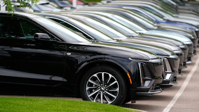 Vehicles sit in a row outside a dealership.