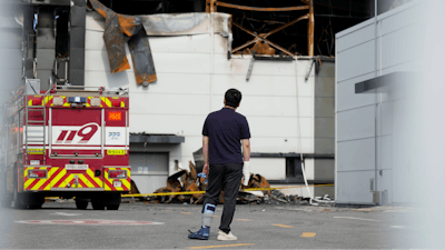 A man wearing a bandage on his right hand and a cast on left leg looks at the site of a burnt battery manufacturing factory in Hwaseong, South Korea, Tuesday, June 25, 2024.