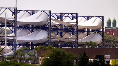 Giant wind turbine blades for the Vineyard Winds project are stacked on racks in the harbor, July 11, 2023, in New Bedford, Mass.