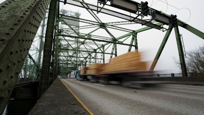 A logging truck drives on the Interstate 5 bridge that spans the Columbia River and connects Portland, Ore., with southwest Washington state, Feb. 13, 2024.