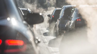 Blurred silhouettes of cars surrounded by steam from the exhaust pipes.