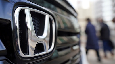 People walk near the logo of Honda Motor Company at a showroom.