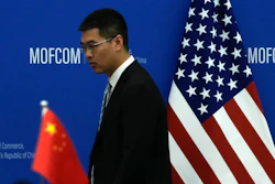 A Chinese official walks by the China and U.S. national flags before a meeting between Commerce Secretary Gina Raimondo and Chinese Minister of Commerce Wang Wentao at the Ministry of Commerce in Beijing on Aug. 28, 2023.