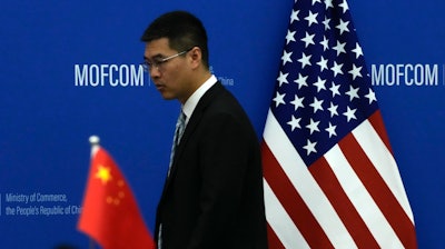 A Chinese official walks by the China and U.S. national flags before a meeting between Commerce Secretary Gina Raimondo and Chinese Minister of Commerce Wang Wentao at the Ministry of Commerce in Beijing on Aug. 28, 2023.