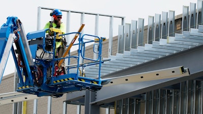 A construction worker maneuvers a lift outside a commercial building site in Mount Prospect, Ill., Tuesday, Aug. 27, 2024.