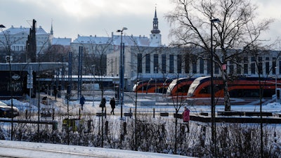 People walk at Baltic train station, with the Stenbock House, left, and St Mary's Cathedral, top, in background, in Tallinn, Estonia.