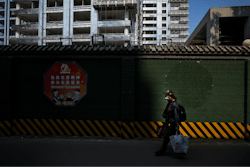 A woman carrying her belonging walks by a luxury housing construction site in Beijing, on Sept. 24, 2024.