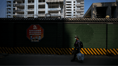A woman carrying her belonging walks by a luxury housing construction site in Beijing, on Sept. 24, 2024.