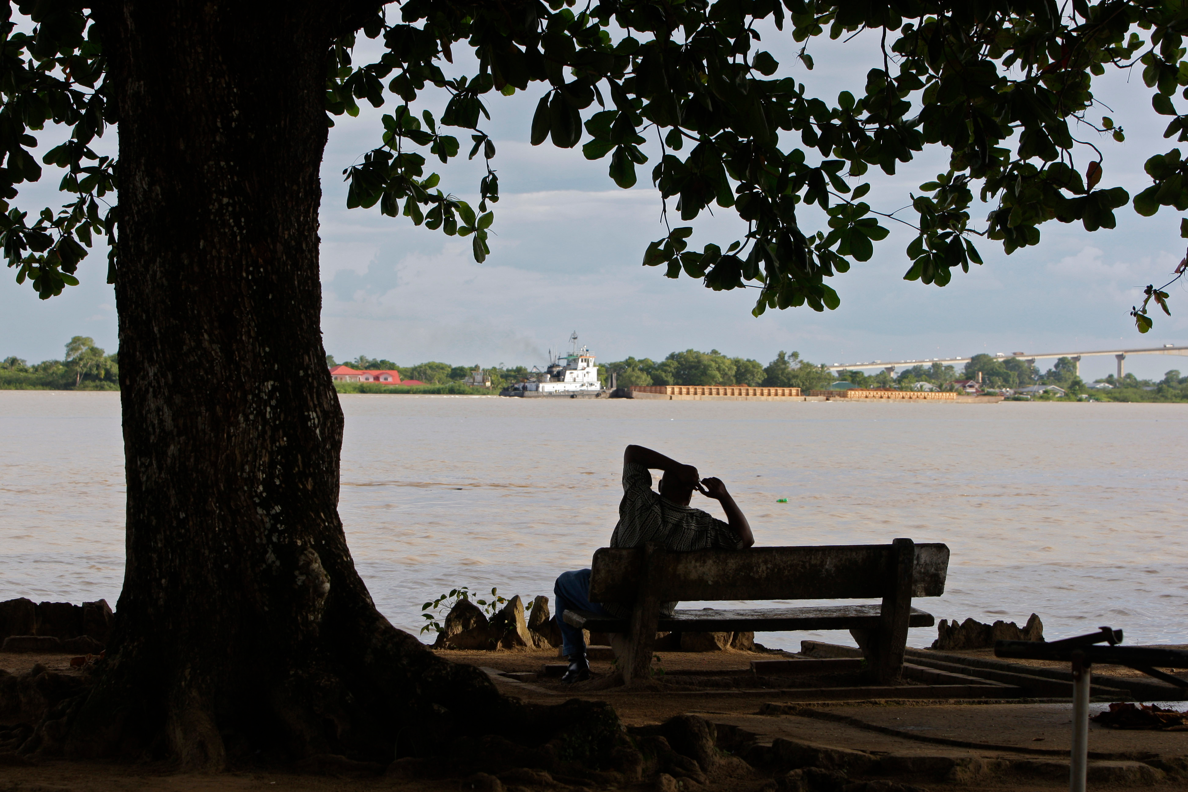 A man sits on the banks of the Suriname River in Paramaribo, Suriname, Aug. 10, 2010.