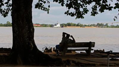 A man sits on the banks of the Suriname River in Paramaribo, Suriname, Aug. 10, 2010.