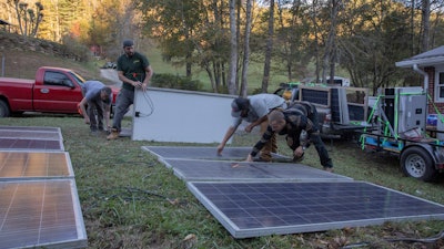 Hayden Wilson, left, Alexander Pellersels, second from left, Jonathan Bowen and Henry Kovacs, right, install a mobile power system at the Beans Creek Church of the Lord Jesus Christ in Bakersville, N.C. on Oct. 9, 2024.