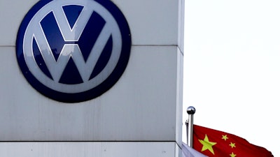A Chinese national flag flutters near a Volkswagen logo in Beijing, Tuesday, April 18, 2017.