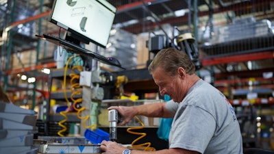 A Winston Industries worker follows the PICO MES instructions on the screen above.