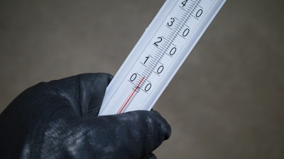 A gloved hand holding a mercury thermometer.