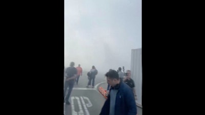 In this image taken from video provided by Justus Rainey, passengers move away from a plane as smoke surrounded the aircraft, in Denver, Thursday, March 13, 2025.
