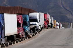 Trucks line up to cross the border into the United States as tariffs against Mexico go into effect, Tuesday, March 4, 2025, in Tijuana, Mexico.