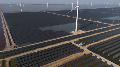 Wind turbines dot the coast line along a giant solar farm near Weifang in eastern China's Shandong province on March 22, 2024.