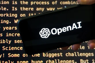 The OpenAI logo appears on a mobile phone in front of a screen showing part of the company website in this photo taken on Nov. 21, 2023 in New York.