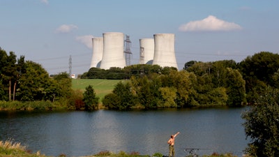 A man fishes with the towering Dukovany nuclear power plant in the background, in Dukovany, Czech Republic, Sept. 27, 2011.