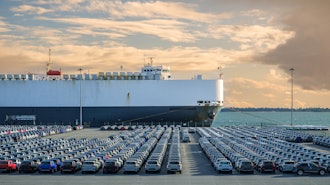 A large auto carrier ship sits at a port. Known as RO-RO vessels, these types of carriers can contain thousands of vehicles.
