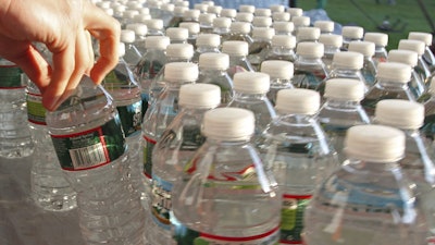 A runner grabs a bottle of water at the athlete's village prior to the start of the 116th running of the Boston Marathon, Hopkinton, Mass., April 16, 2012.